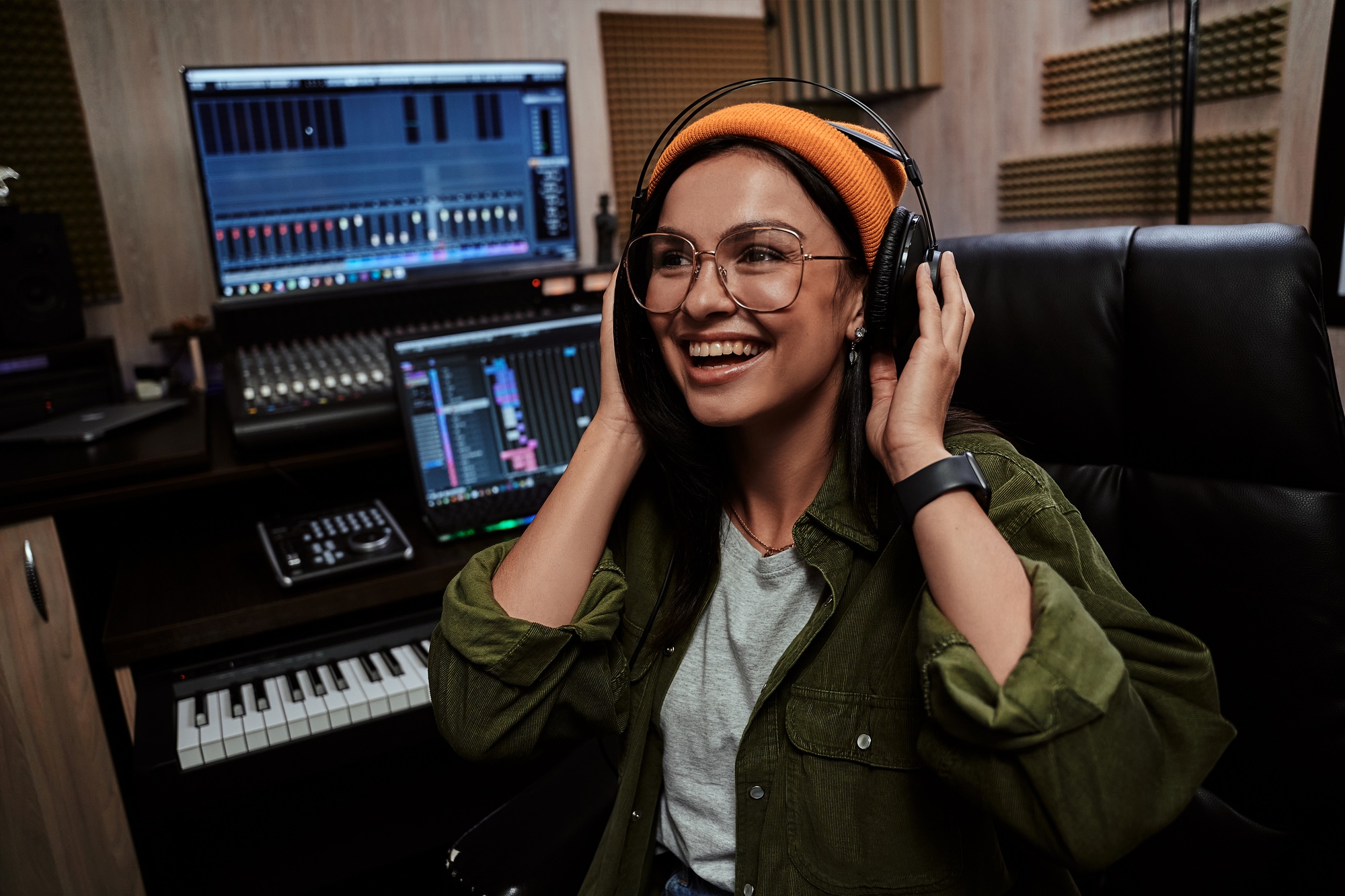 Portrait of beautiful young brunette, female artist smiling aside, adjusting headphones while