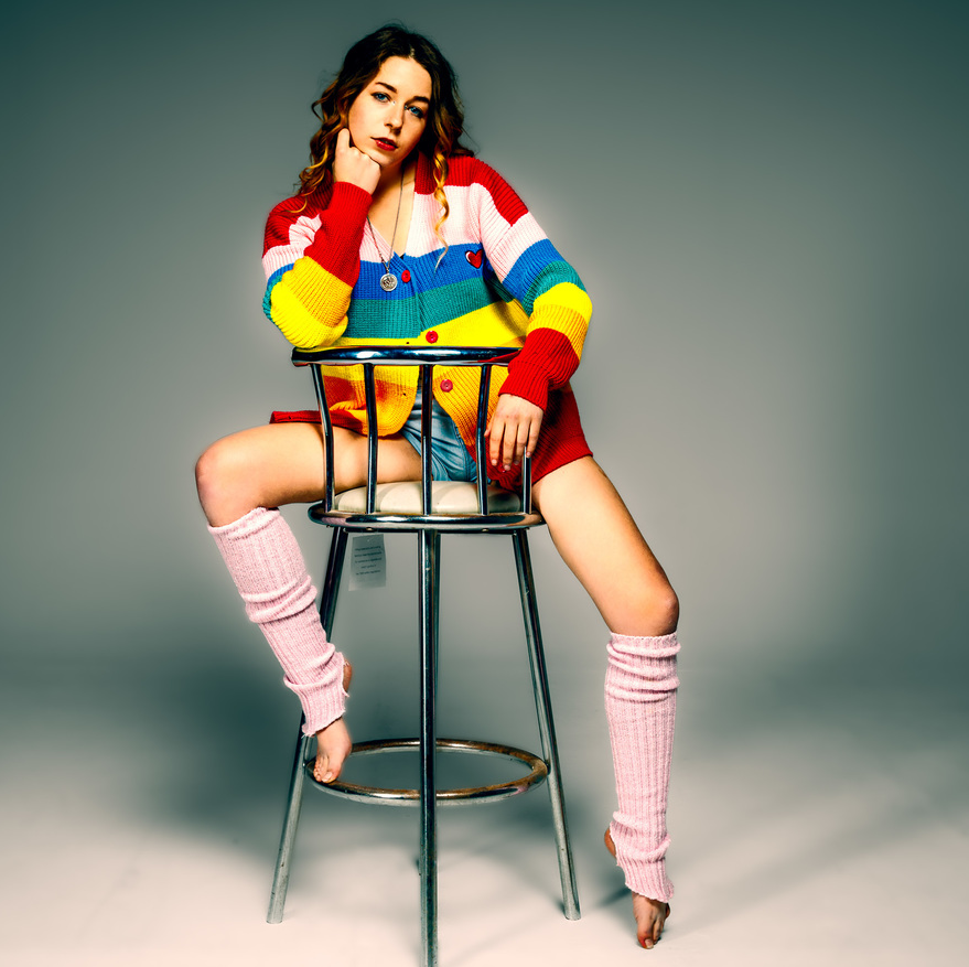 Girl on high stool with rainbow cardigan